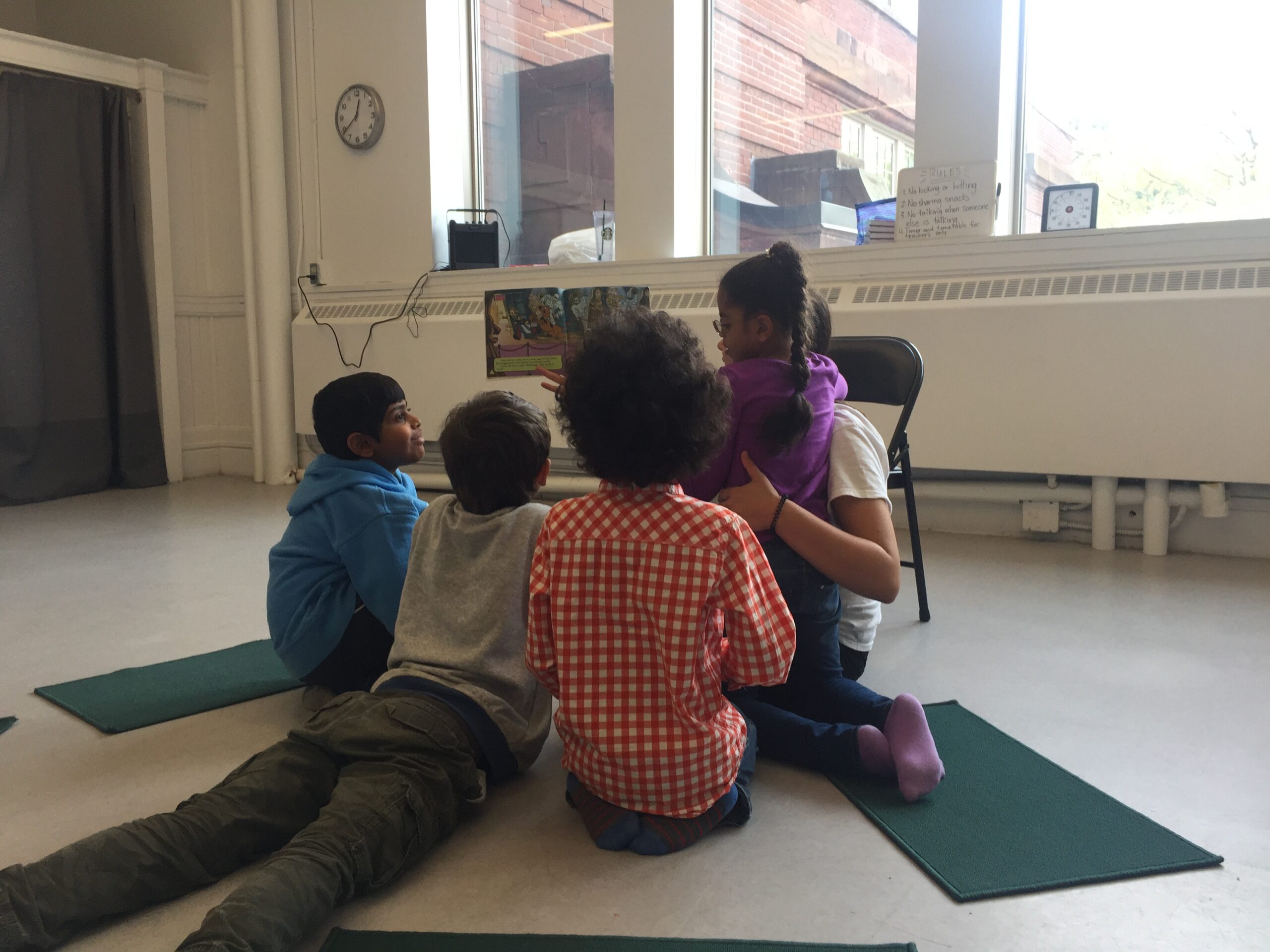 a group of children sitting on yoga mats in a room