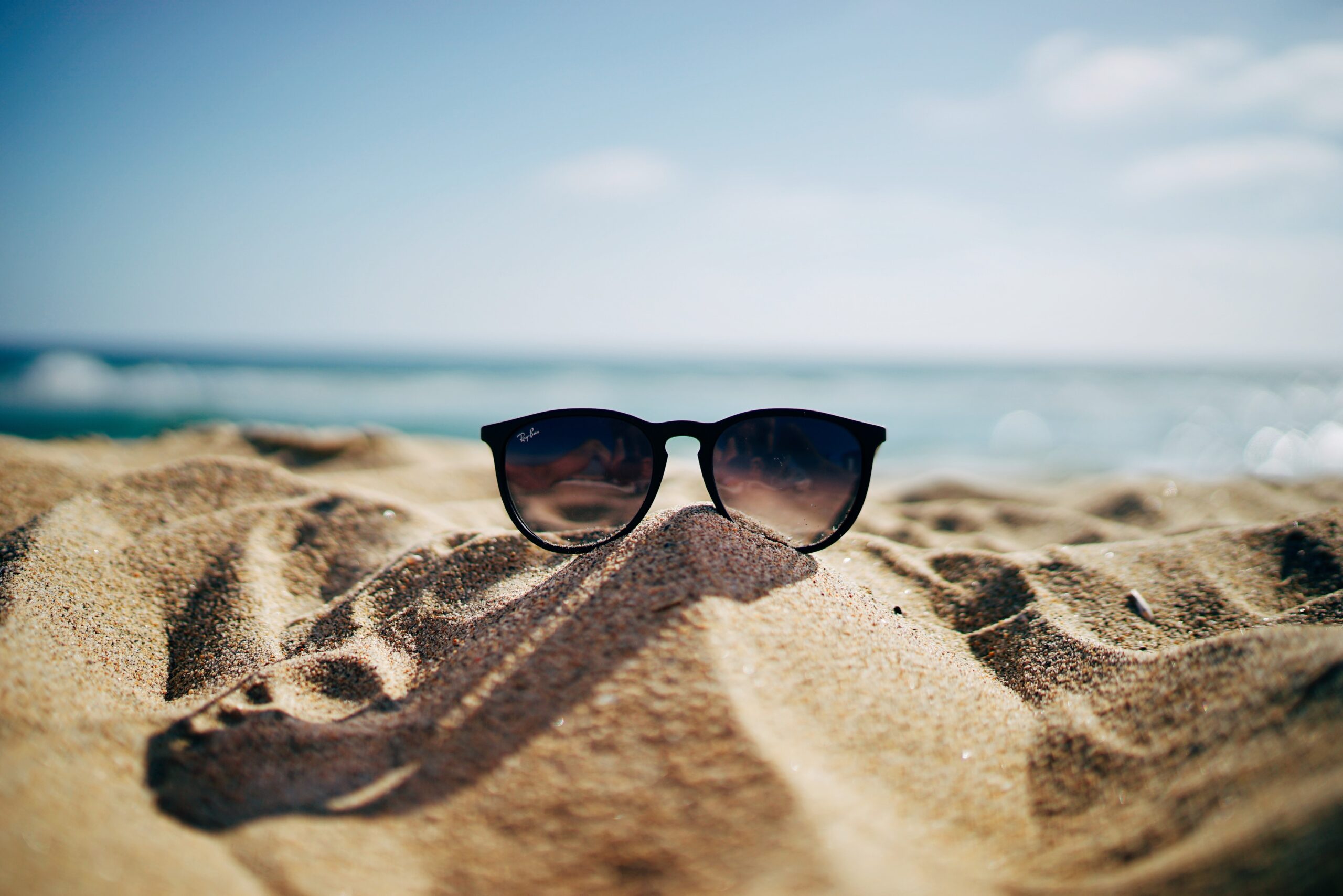 a pair of sunglasses sitting on top of a sandy beach