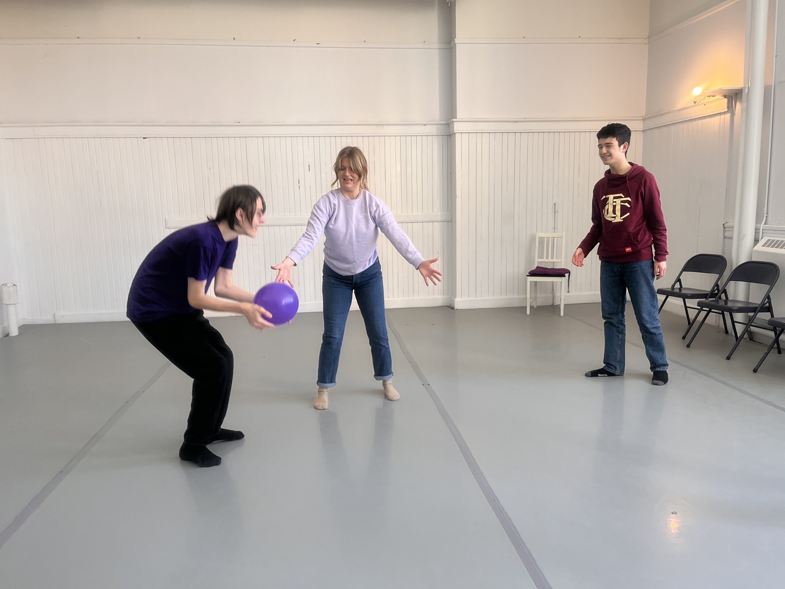 three people in a room with one holding a purple balloon