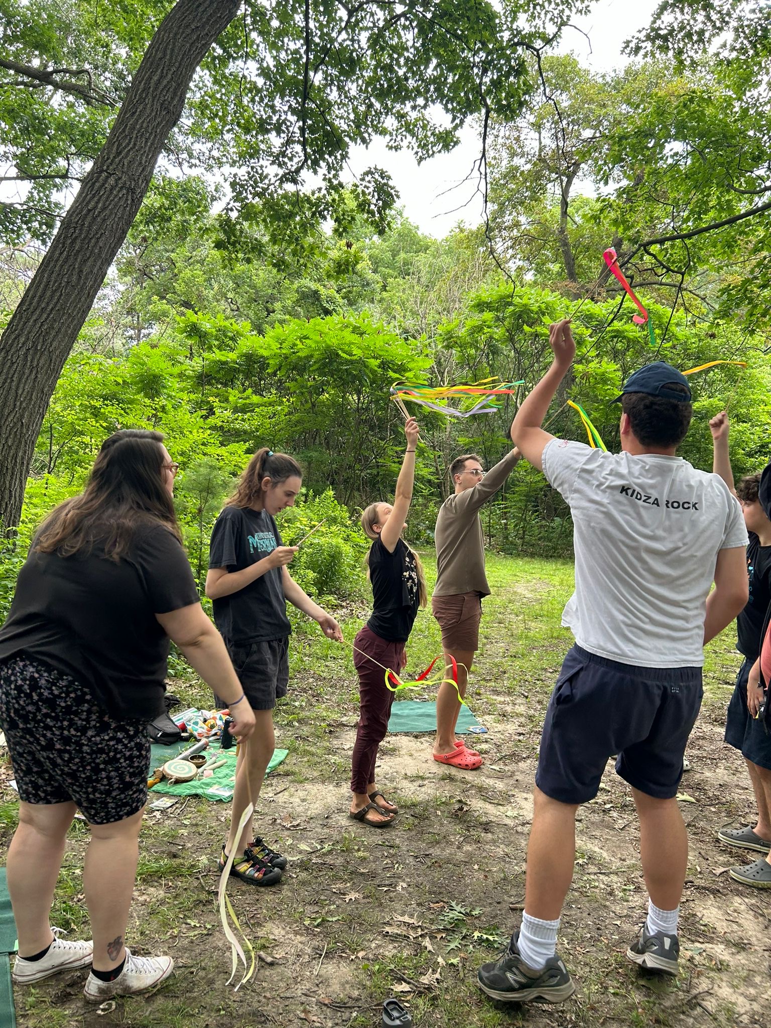 a group of people playing with a kite in the woods