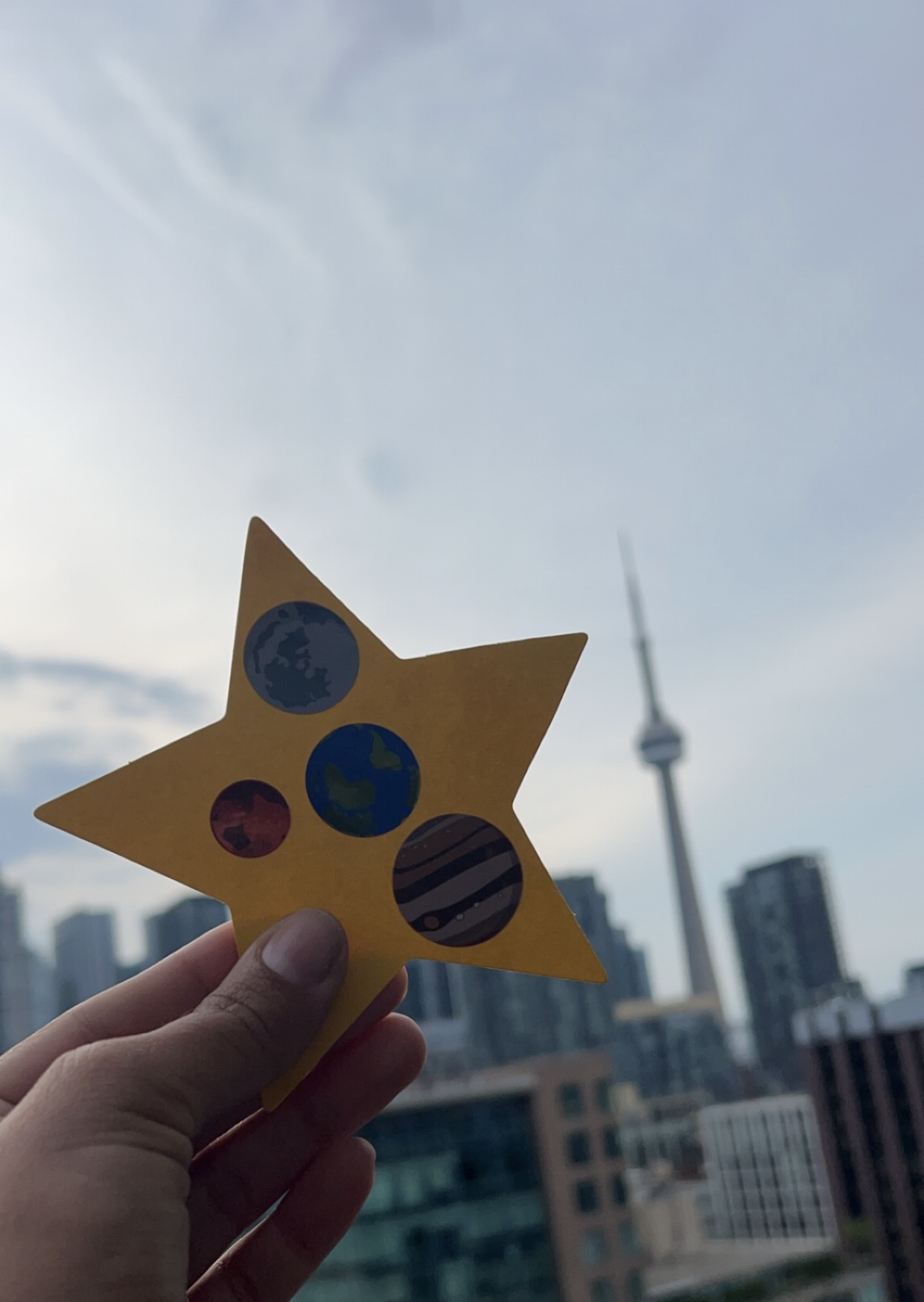 a person holding up a yellow star with a city in the background