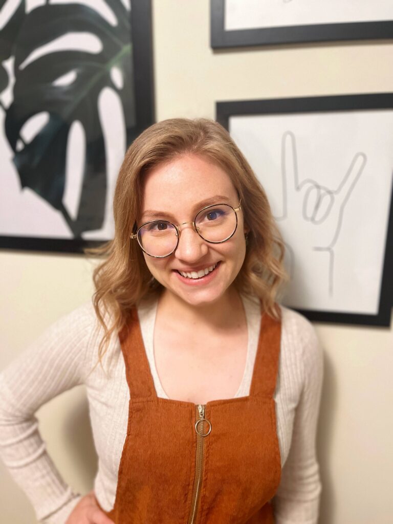 a woman standing in front of a wall with pictures on it