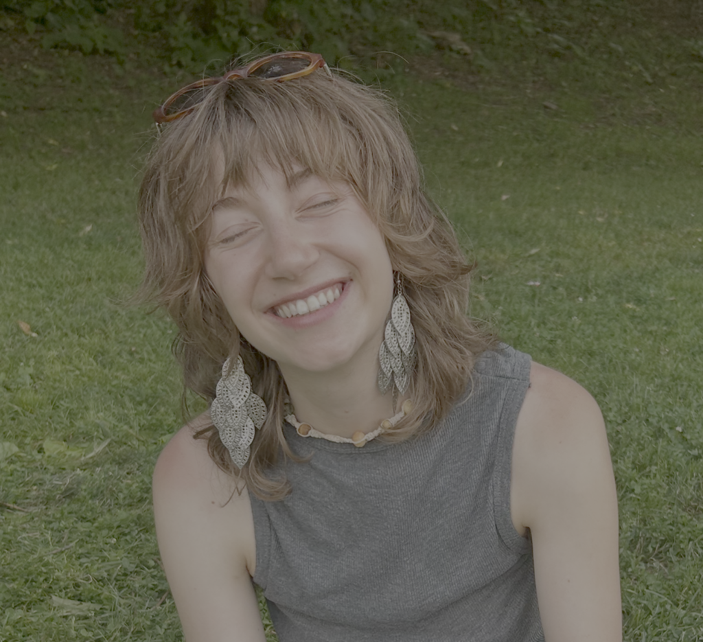 a woman sitting in the grass with her eyes closed