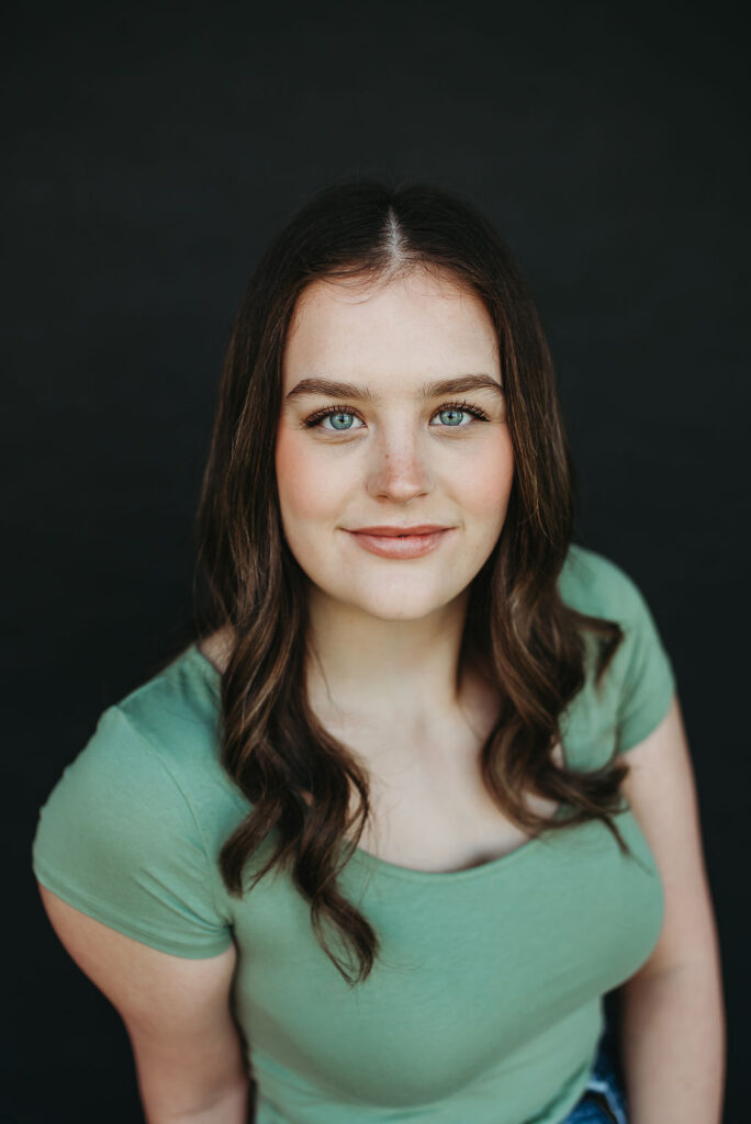 a girl in a green shirt posing for a picture